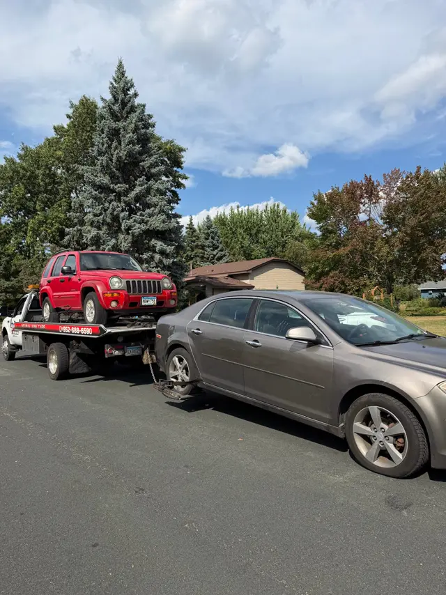 Jeep Liberty on the flatbed and a sedan being hooked in the Twin Cities