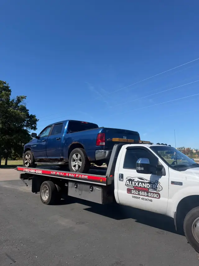 Blue Ram pickup on a flatbed tow truck in Minnesota
